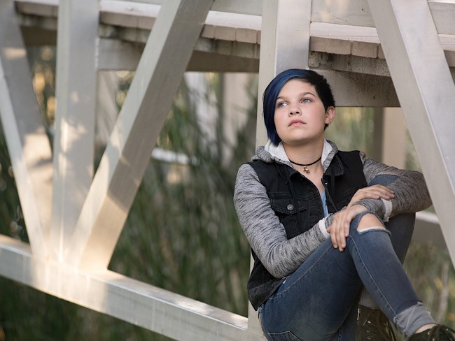teen sitting on a walking bridge