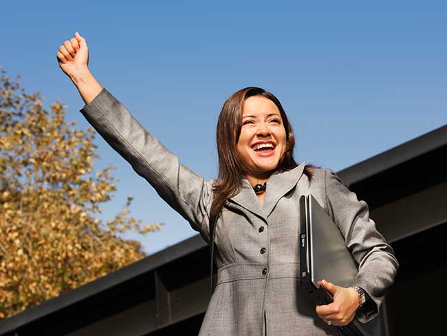 A young woman in a business suit with a fist raised over her head