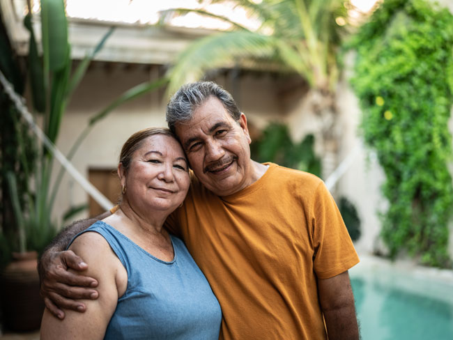 senior couple standing by a swimming pool and smiling