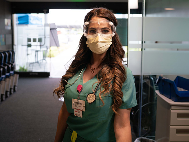 woman dressed in scrubs wearing goggles and protective mask