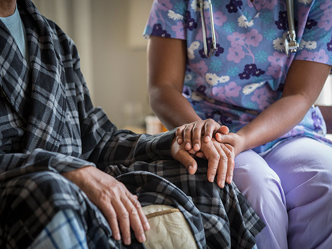 A caregiver holds a patients hand