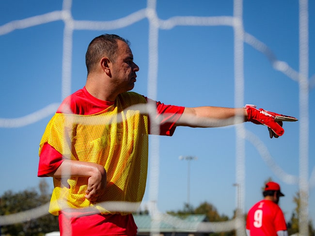 From behind a soccer net, we see a goalie pointing at something off camera. 