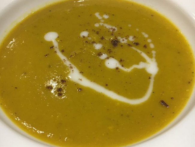 Bowl of Indian squash lentil soup with a swirl of coconut milk and a sprinkle of garam masala