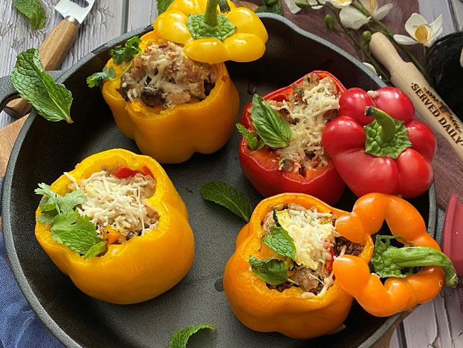 Overhead photo of stuffed bell peppers in a pan on a wooden table.