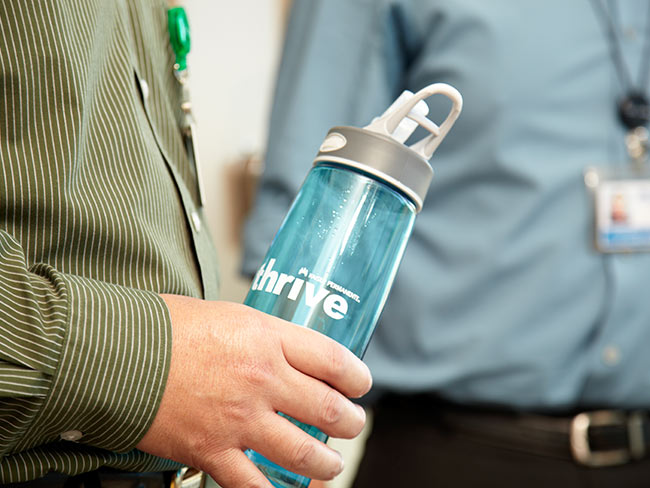 hand holding water bottle with the Kaiser Permanente Thrive logo